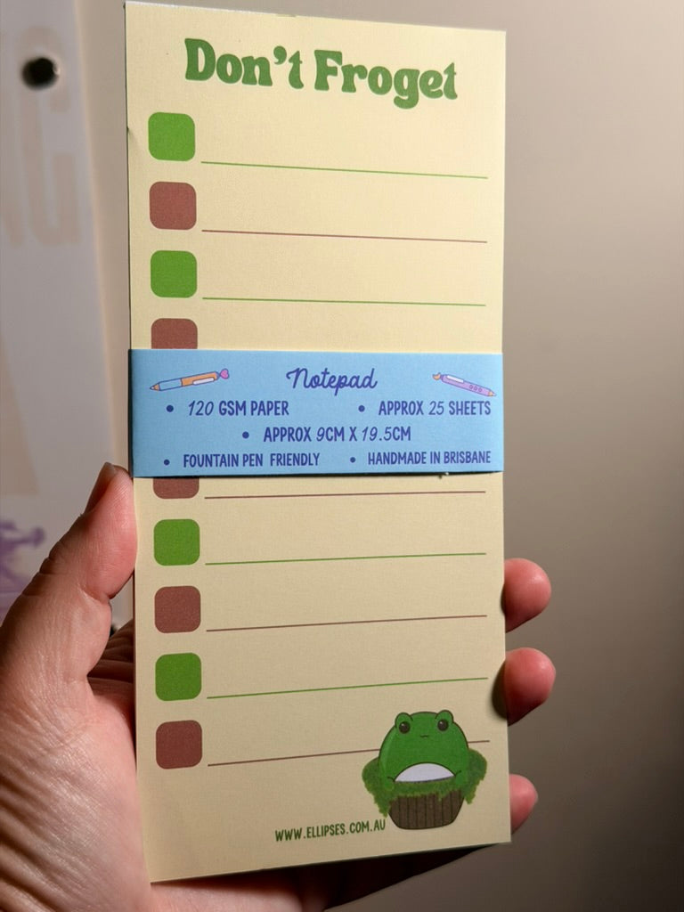 Notebook titled 'Don't Froget' held by a hand with a light background