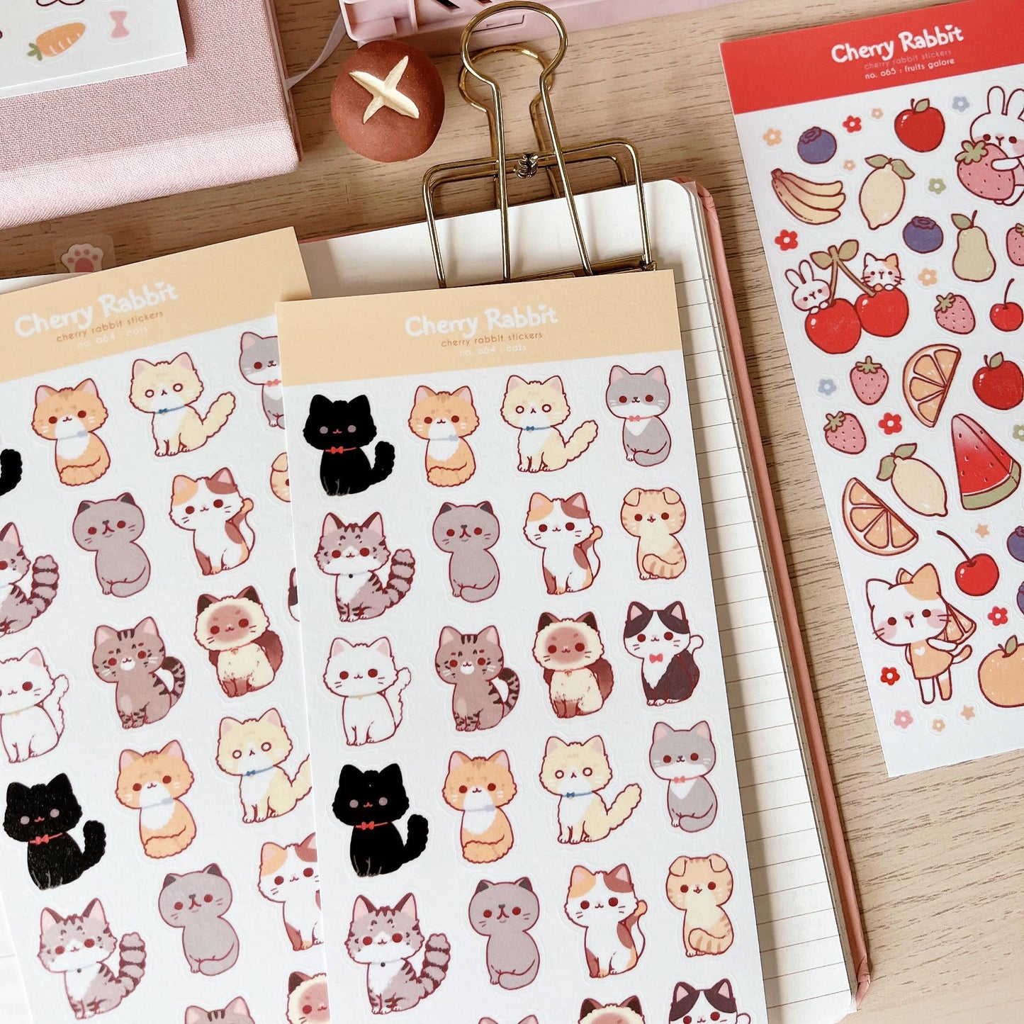 Sticker sheet with cut cats with a notebook and wooden desk background