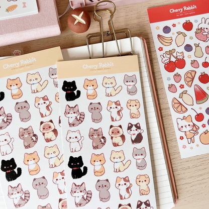 Sticker sheet with cut cats with a notebook and wooden desk background